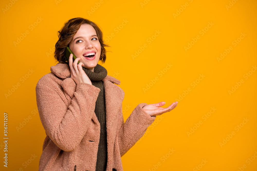 Poster Photo of funny cheerful pretty lady hold telephone speaking friends sharing fresh news wear casual modern style pink coat warm green knitted pullover isolated yellow color background