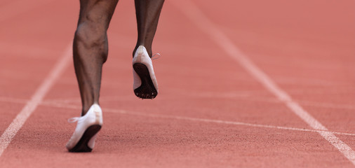 African-american male sportsman running on stadium track, dynamic run of sprinter in a stadium	