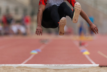Athlete in long jump during competition, performing triple long jump on races