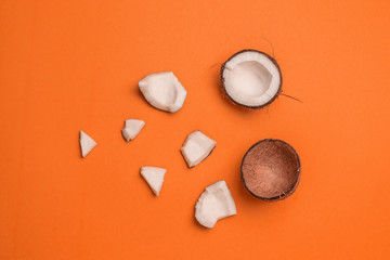 Obraz na płótnie Canvas Half a coconut, pieces of coconut on an orange background. Horizontal position