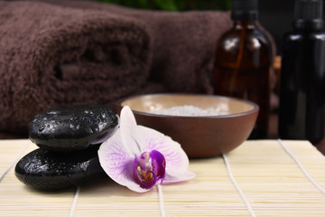Obraz na płótnie Canvas Massage stones with orchid stock images. Spa and wellness setting stock images. Pile of black stones. Black stones on a nature background. Spa-concept with zen stones and orchid flower stock images