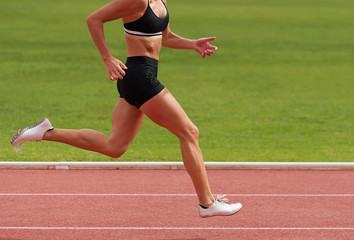 Obraz premium Female athlete running on stadium track, dynamic run of sprinter in a stadium