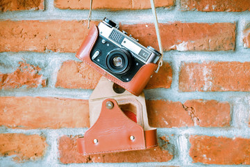 Vintage analog film camera with lens on a brick wall background.