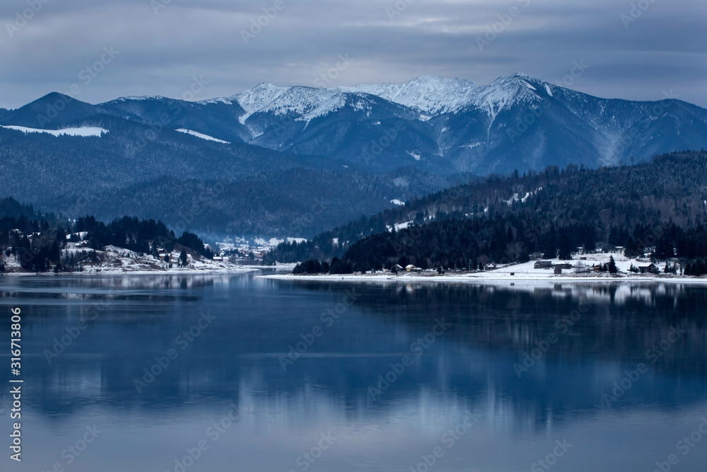 Wall mural Frozen lake and pine trees in snow at Colibita. Romania early morning winter scen.