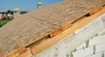 Fototapeta na wymiar Roofing construction house roof with covering oriented strand boards (OSB) before asphalt shingles installation.
