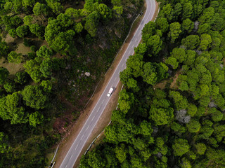 Aerial view of a vehicle on the road through a deep forest. Bird eye view of a Green Forest road. Drone shot.