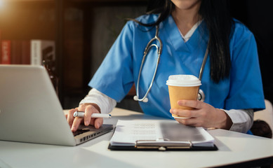 Female doctor working on desk with laptop computer and paperwork in the office. Medical and doctor concept.