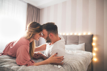 Naklejka na ściany i meble Couple in bed holding hands.