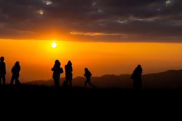 Fototapeta na wymiar Group of silhouette people on top of a mountain on sunset.