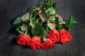 Fototapeta na wymiar Red roses on a black wooden background. Bouquet of flowers on dark wood boards