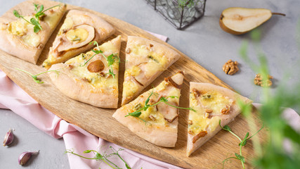 Homemade pizza slices with pear, walnuts, dorblue cheese and mozzarella with ingredients on gray background. Side view. Recipe, menu, pizzeria concept