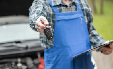 Mechanic delivering car keys after car engine checking
