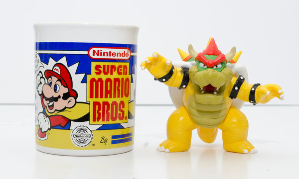 london, england, 05/05/2018 a super mario official nintendo 1990s super mario bros mug coffee cup and bowser toy isolated on a white background. official merchandise.
