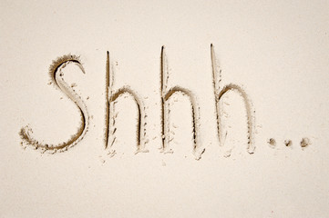 Shhh... message handwritten in textured script in smooth sand on a sunny beach