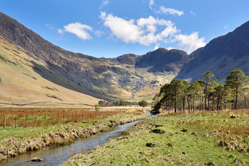 The valley of Gatesgarth and Warnscale Bottom with mountain summits of Fleetwith Pike and Hay Stacks high above on a sunny blue sky spring day in the Lake District.