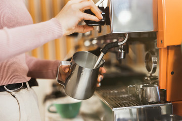 process of frothing milk with a cappuccino maker in order to prepare latte macchiato drink, barista...