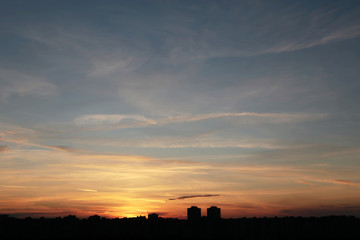 Sunrise over the city, scenic view. Sky with clouds in soft colors above silhouettes of high-rise buildings, colorful cityscape for background