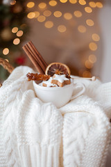Fototapeta na wymiar wicker basket, knitted sweater, dried citruses, cinnamon sticks, Christmas cookies, Christmas lights. Cozy.