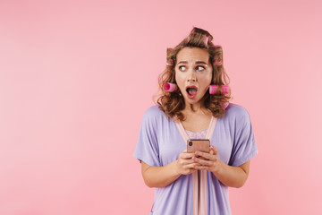 Image of young scared woman expressing surprise and using cellphone