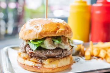 Hamburger with beef burger cutlet, blue cheese, spinach, french fries and ketchup served on tray.