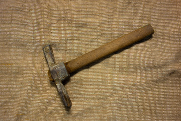 Miner hammer like pickaxe or mattock on bagging fabric background. Closeup view of rustic old hand tool for hard working to extract fossils or concept of block chain currency mining
