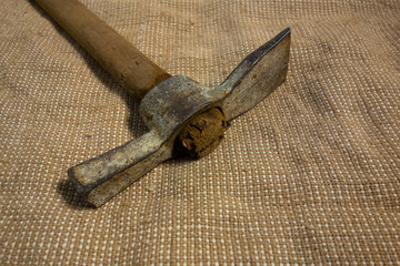 Miner hammer like pickaxe or mattock on bagging fabric background. Closeup view of rustic old hand...