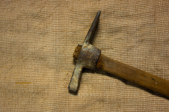 Miner hammer like pickaxe or mattock on bagging fabric background. Closeup view of rustic old hand tool for hard working to extract fossils or concept of block chain currency mining