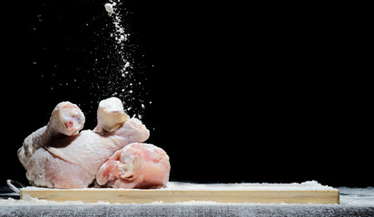 chicken, chicken drumstick in flour with flour dust flying in different directions on a black background
