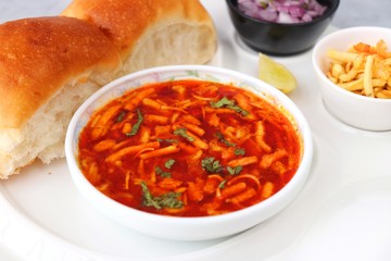 Spicy Misal Pav or usal Pav is a traditional snack or Chat food from Maharashtra, India. Served with chopped onion, lemon wedges and farsan. Selective focus with copy space