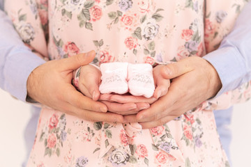 Young pregnant woman holding baby booties - Gender Reveal - It's a Girl !