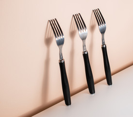 Forks standing on a wall, with big shadows between them. Silverware and their shadows on the wall