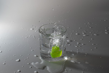Colorful cubes dropped in a glass full of water, making beautiful splashes and wetting the table