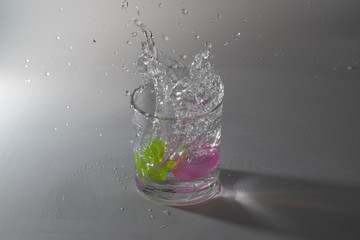 Colorful cubes dropped in a glass full of water, making beautiful splashes and wetting the table