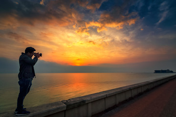 Photographer in seaside with beautiful sunrise background. Khobar Corniche -Saudi Arabia.