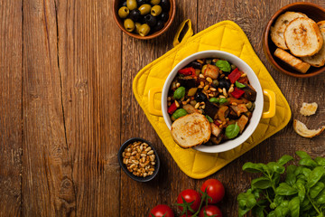 Traditional Italian caponata, served with croutons in a yellow, sunny pot. Decorated with basil and...