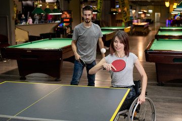 Disabled girl in a wheelchair playing table tennis