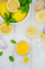 Homemade Lemon curd in glass jar with fresh lemons on a white wooden background. Vertical orientation, top view.