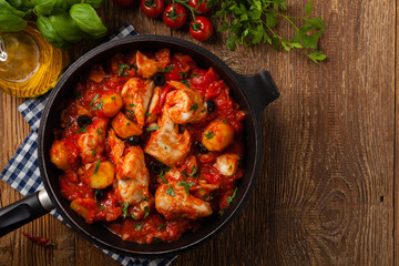 Traditionally prepared cod in Spanish. Served in tomato sauce with boiled potatoes, olivki and basil. Top view.
