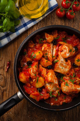 Traditionally prepared cod in Spanish. Served in tomato sauce with boiled potatoes, olivki and basil. Top view.