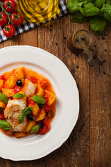 Traditionally prepared cod in Spanish. Served in tomato sauce with boiled potatoes, olivki and basil. Top view.