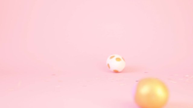 Assorted colored golden and pink eggs and shiny sweets falling on a pink table. Minimal video concept for celebration.