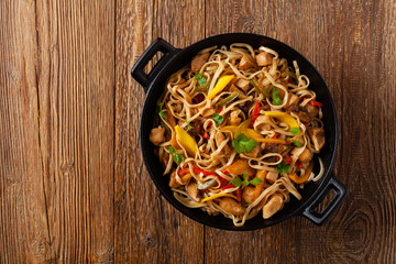 Fried chicken with mango and coconut milk with noodles. Prepared in a wok. Top view.