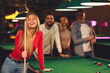 Group of friends play billiards at night out - obrazy, fototapety, plakaty