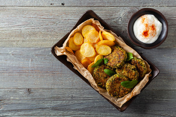 Vegetarian spinach and broccoli meatballs, served with yogurt dip and toasted potatoes. Top view.