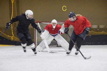 Full length action shot of female hockey team fighting during match, copy space