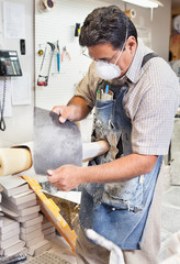 Mature male worker polishing prosthetic limb in workshop