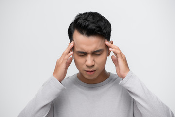 Young asian man standing over isolated white background with hand on head for pain in head because stress. Suffering migraine.