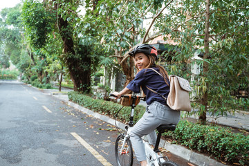 young women riding folding bikes on the road wearing helmets and carrying bags to work