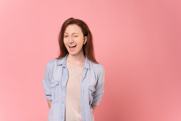 Close-up portrait of a cute and cheerful caucasian young woman having a fun winking eye posing over...