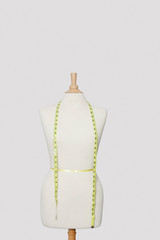 Measuring tape on dressmakers model over colored background